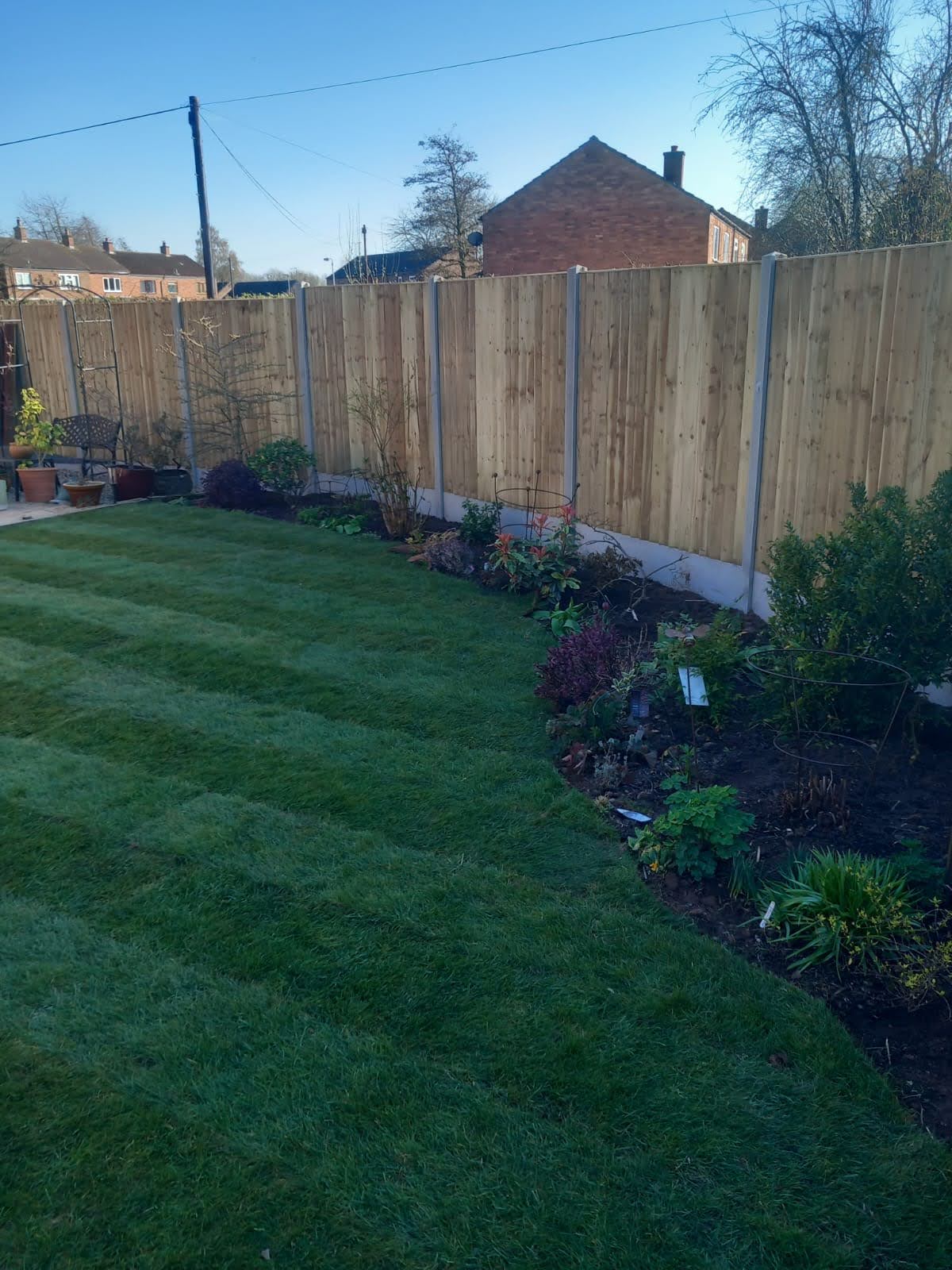 Closeboard fence with concrete posts beside a lawn