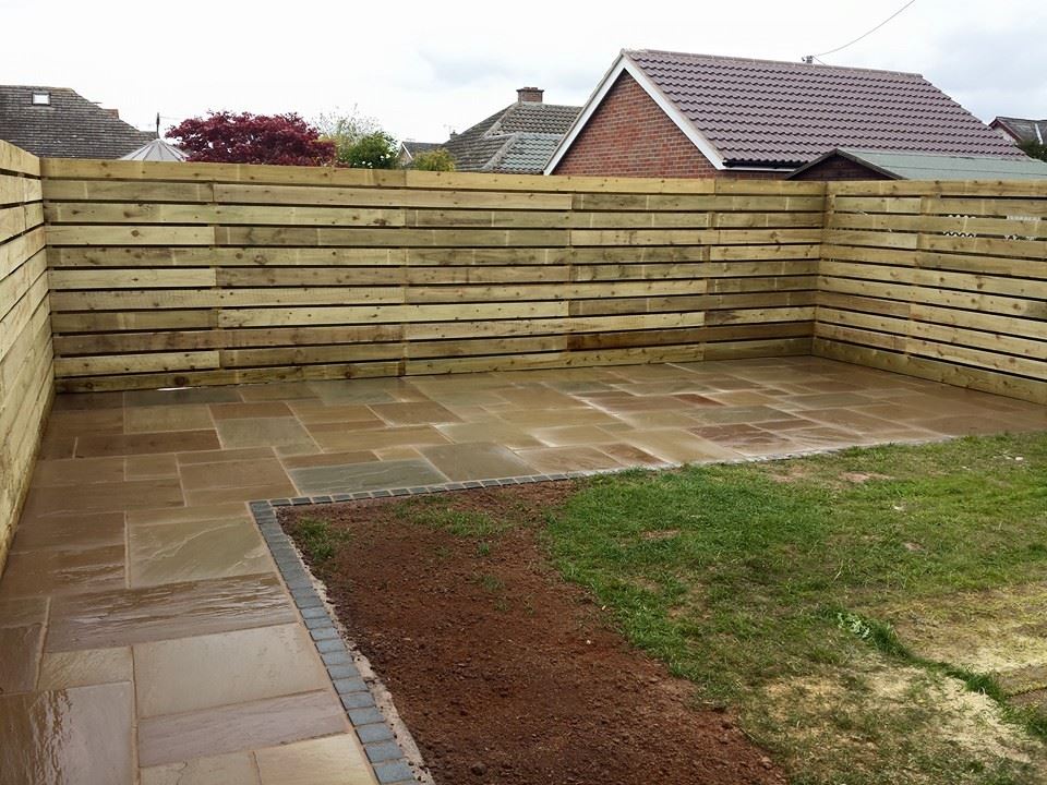 Hit-and-miss fencing beside sandstone paving